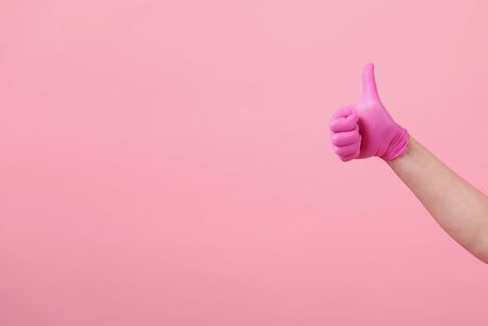 Hands of a girl in pink latex gloves on pink background. Virus protection, medical sterilityの写真素材