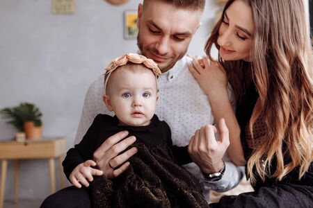 mom, dad and little girl having fun and hugging at home on bed. mothers, fathers and babys day. Happy family holiday indoors. family look. Happy young family spending time togetherの写真素材