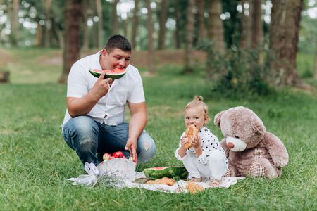 Happy smiling young father and daughter on picnic in park at summer day. The concept of summer holiday. Father's, baby's day. Spending time together. selective focusの写真素材