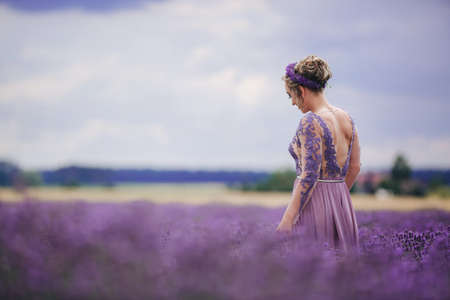 Portrait of beautiful romantic woman in purple dress in field of lavenderの写真素材