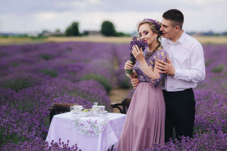 Young couple in love hugging in a lavender field on summer day. girl in a luxurious purple dressの写真素材