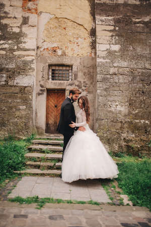 Young stylish newlyweds are hugging behind old rustic wooden door. wedding dayの写真素材