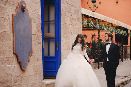 Stylish bride and groom gently hugging on european city street. Gorgeous wedding couple of newlyweds embracing near ancient building. romantic sensual moment of newlyweds.