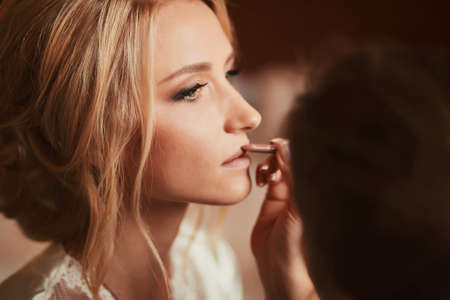 Make-up artist doing make up for young beautiful bride applying wedding make-upの写真素材