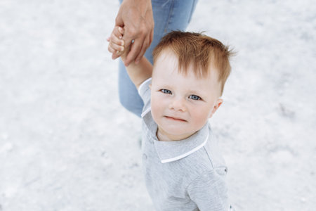 Portrait of a cute little boy on the background of white sand in the nature. Happy face is close