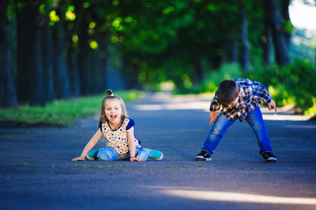 Children's love, a little boy and a girl, having fun, laugh and smile, and kiss outdoors.