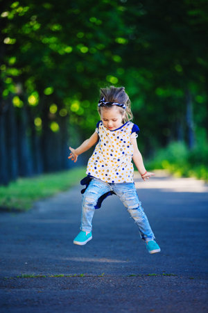 beautiful little girl with a wreath of poppies in a white dress and collects a bouquet of...