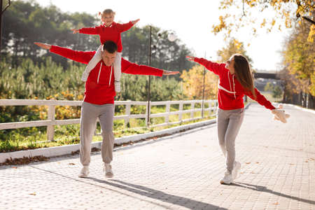 Daddys carrying a baby daughter on his shoulders in the autumn park. The concept of family holiday. Fathers, mothers, babys day. Spending time together. Family look.の写真素材