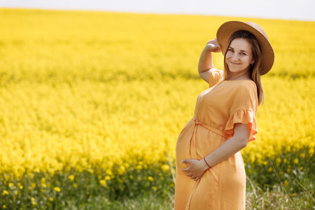 Beautiful young pregnant woman in long dress in the green field on summer day. Happy maternity and pregnancy concept.の写真素材