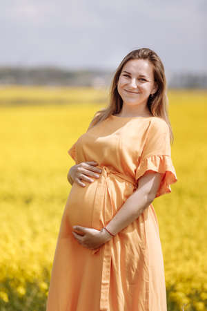 pregnant woman among the flowers. enjoys the beauty of spring among the flowering trees.Reuniting with nature in a flowering spring gardenの写真素材