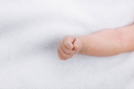 Closeup of newborn baby girl hand on white blanket outdoor. maternity and childhood concept....
