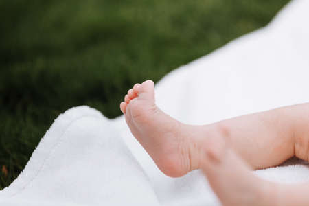 Closeup of newborn baby girl feet on white blanket outdoor. maternity and childhood concept.の写真素材