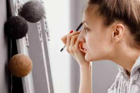 A young girl paints her eyelashes with mascara. Face close-up. facial care.