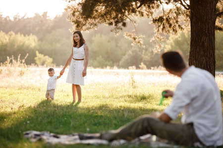 happy family mom dad and baby son happy in nature spending time together on summer sunny day. The concept of a fun holiday outdoors. Happy childhoodの写真素材