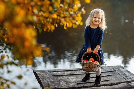 girl reads a book in autumn by the river. lonely young woman reads a book on a wooden bridge.の写真素材