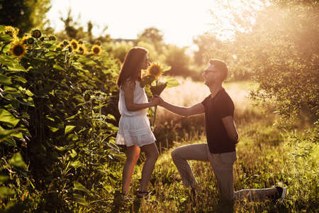 Beautiful couple in sunglases having fun in sunflowers field. A man and a woman in love walk in a field with sunflowers, a man hugs a woman. selective focus.の写真素材