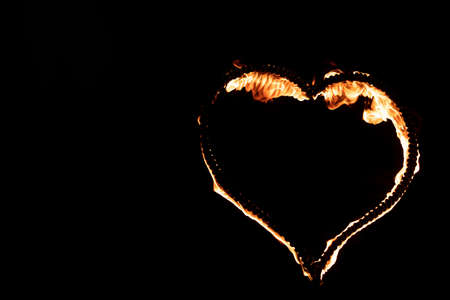 Burning heart with flames. Isolated on dark background. fire show in night. happy valentine's day card. bengal fire burning heart. space for text. wedding or valentine concept. happy new yearの写真素材