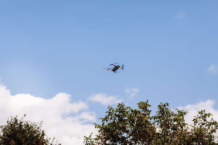Quadcopter drone in sky. Small drone flies in sky over the park taking video and photos. Remote control air delivery and spy. selective focusの写真素材