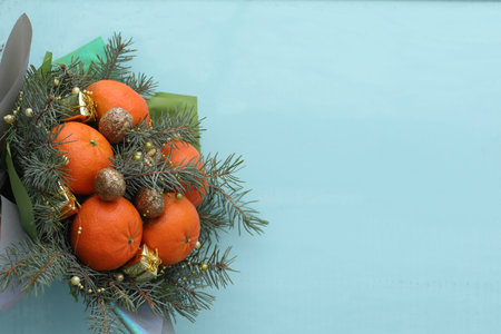 Christmas bouquet of fir branches, mandarins and little gift boxes on blue background. New Year....