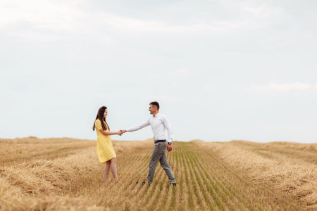 Young beautiful couple is hugging in the field in summer. woman with long hair and man with stylish...