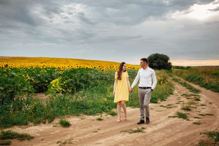 Young beautiful couple is hugging in the field in summer. woman with long hair and man with stylish haircut.の写真素材