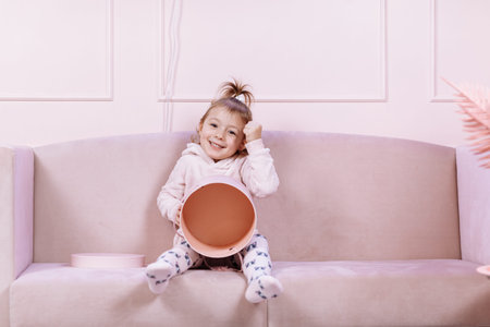 Cute little girl is lying on pink sofa, smiling and looking at the camera. happy childhood.の写真素材