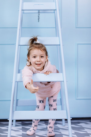 Smiling beautiful little girl in unicorn pink costume is smiling and having fun on a blue wall background. happy childhoodの写真素材
