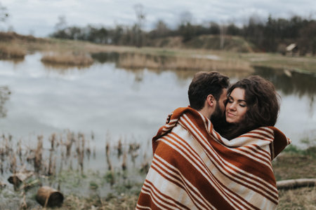 two caucasian lovers near the lake. Young couple is hugging on autumn day outdoors. A bearded man and curly woman in love. Valentine's Day. Concept of love and family.の写真素材