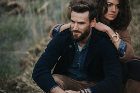 two caucasian lovers near the lake. Young couple is hugging on autumn day outdoors. A bearded man and curly woman in love. Valentine's Day. Concept of love and family.の写真素材