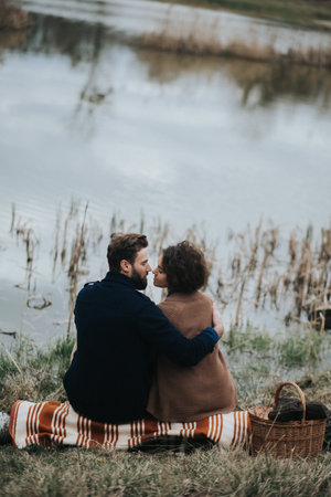 stylish hipster caucasian couple hugging at lake in autumn. man and woman in love in modern outfit.の写真素材