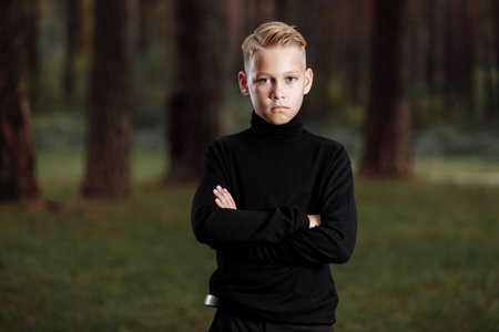 Stylish attractive young guy with a fashionable hairstyle in a trendy black outfit enjoys an outdoor vacation in the parkの写真素材