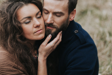 caucasian man is playing guitar with woman by the lake. Young couple is hugging on autumn day outdoors. A bearded man and curly woman in love. Valentine's Day. Concept of love and familyの写真素材
