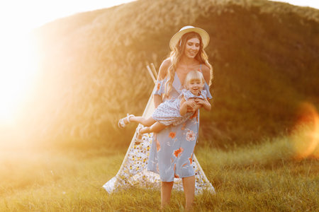 black and white photo. Portrait of a mother is having fun with daughter on nature on summer day vacation. Mom and girl playing in the park at the sunset time. Concept of friendly familyの写真素材