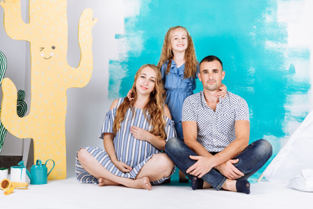 Portrait of a happy family father, pregnant mother, little daughter having fun together isolated...