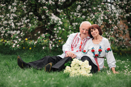 Beautiful couple in national Ukrainian embroidered shirts shirt, sitting on grass. wedding...