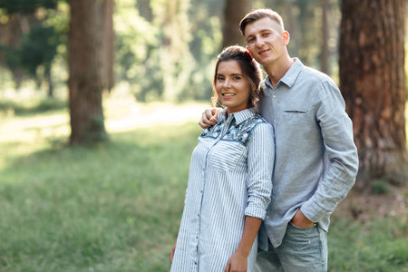 Outdoor shot of young happy couple in love on sunny day on nature. Man and woman hugging, sunlight...