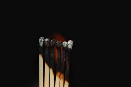 Burning matches on black background. matchsticks on fire in row of burning is sequence while one match stay down from burning to avoid fire connecting against black background.の写真素材