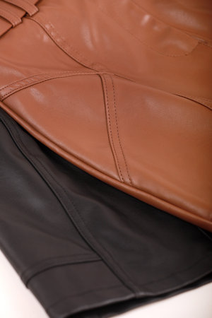 two women leather mini skirts black and brown folded on a white table.