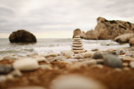 Pyramid stones on the seashore on a sunny day on the blue sea background. Happy holidays. Pebble...