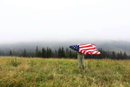 Little cute 7 years old girl playing with colorful kite on foggy day in the mountains. happy child in green jumpsuit and cap is having fun outdoors. active family vacation.の写真素材