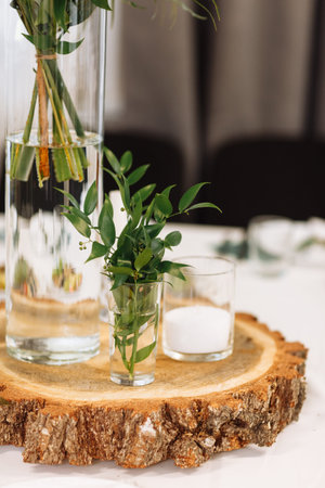 Table setting at wedding reception. Floral compositions with flowers and greenery, candles on...