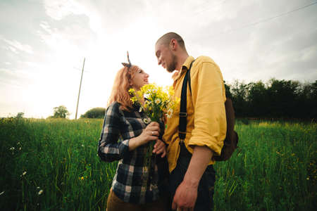 A man and a woman are hitchhiking. A young couple goes hitchhiking around the country. Free hitchhiking trip. A lover who travels free by hitchhiking. The couple goes traveling. Couple by the road.の写真素材
