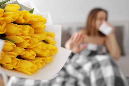happy woman with yellow tulip flowers in bed after shower with towel on head enjoying romantic gift...
