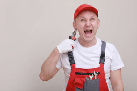 male worker In red working form and cap with cellphone in hand and communicates anxiously and shocked with customers isolated on white background. of the service delivery is a career.の写真素材