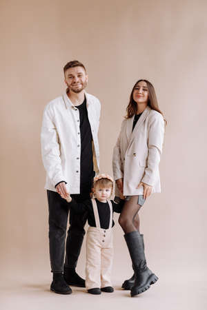 young parents mom and dad are celebrating birthday their two years old child. family light and blowing out the candles on the cake with flowers on the background of birthday decor with pink ballsの写真素材