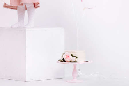 Beautiful white cream cake decorated with 2 year old candle and roses in white studio. Birthday party - Concept of a year of birth, party, celebration of life and memorable momentsの写真素材