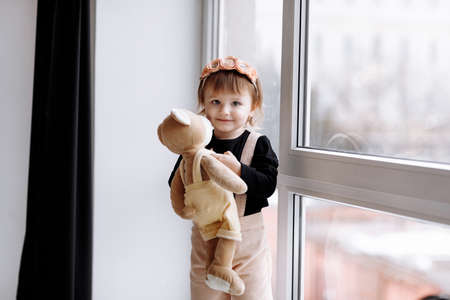 happy birthday 2 years old little girl in pink dress. white cake with candles and roses. Birthday decorations with white and pink color balloons and confetti for party on a white wall. Happy birthday.の写真素材