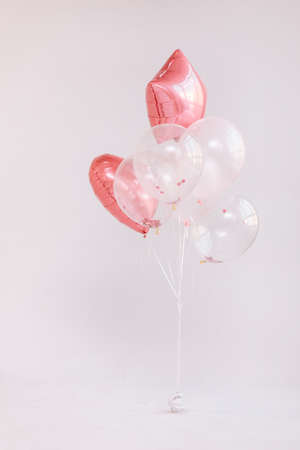 Birthday decorations with white and pink color balloons and confetti for party on a white wall. Happy birthday.の写真素材