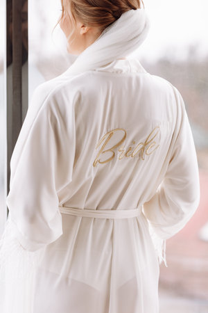 Morning of bride. Gorgeous bride. beautiful woman with long hair in a white robe at the window. the...