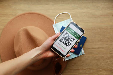 a passport and a smart phone with a certificate of vaccination against the Covid-19 disease. focus on the smart phone. Health Passport concept. travel the worldの写真素材